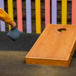 Girl is about to toss a beanbag into a hole