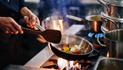 A chef fries vegetables over a flame