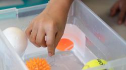 A student reaches into a plastic bucket with different toy rafts