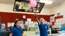 Students in a science classroom keep a balloon aloft 