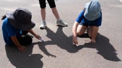 Students sit on a sunlit playground