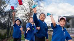 Students in a line face the camera and throw bean bags