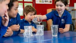 3 students observe a fourth testing their waterproofing experiment