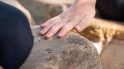 Student touching a weathered rock