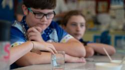 Students observe a metal bracket in a clear liquid
